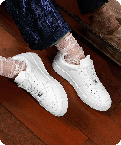 Close up of white sneakers worn on a wooden floor